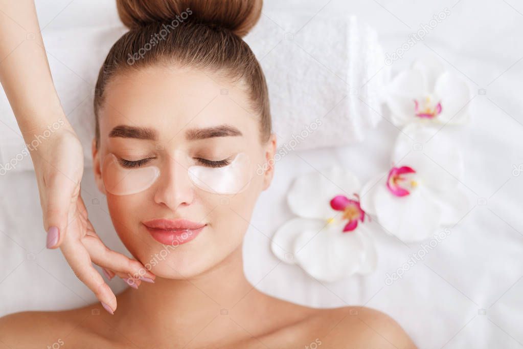 Under eye treatment. Woman with patches, relaxing in spa center