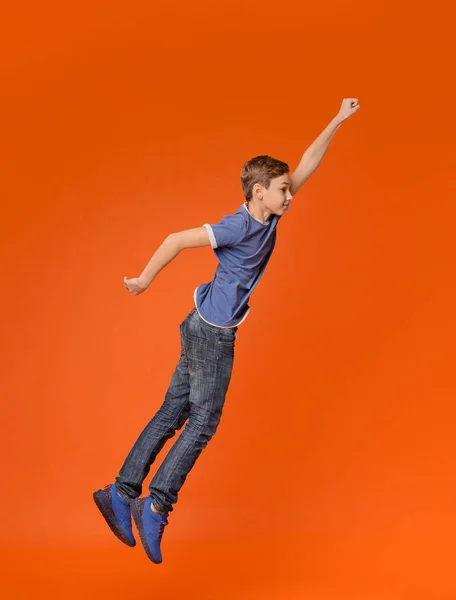 Lille dreng hoppe med hævet knytnæve som en superhelt - Stock-foto
