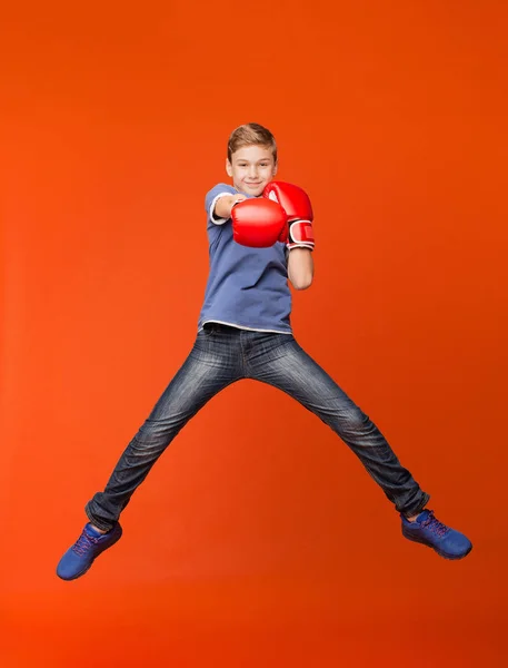 Lite kid gestikulerande med boxhandskar på orange — Stockfoto