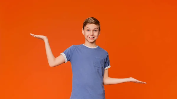 Hesitant boy spreading hands sideway with empty space — Stock Photo, Image