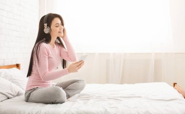 Rahatlatıcı ve yatakta müzik dinlemek genç güzel kadın