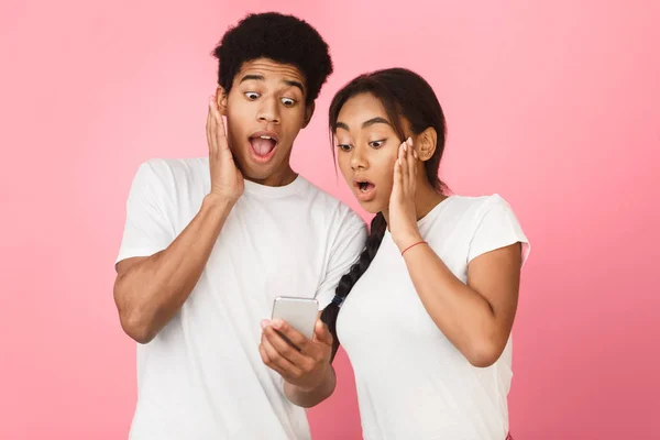 Isi kejutan. Pasangan menggunakan smartphone, latar belakang pink — Stok Foto