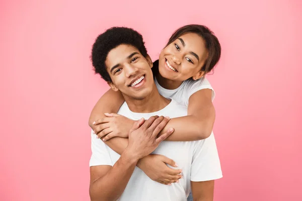Man ger piggyback rida till sin flickvän på rosa bakgrund — Stockfoto