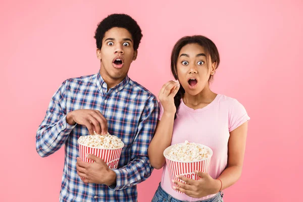 Pareja impactada viendo películas de miedo, sosteniendo un cubo de palomitas de maíz —  Fotos de Stock