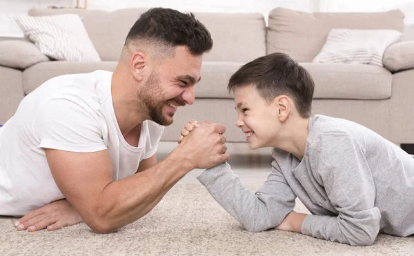 Father and son compete in armwrestling at home — Stock Photo, Image