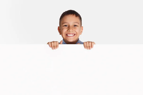 Publicidad. Pequeño niño de pie detrás de la bandera en blanco — Foto de Stock