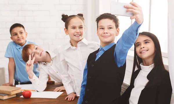 Niños felices tomando selfie en el aula escolar —  Fotos de Stock