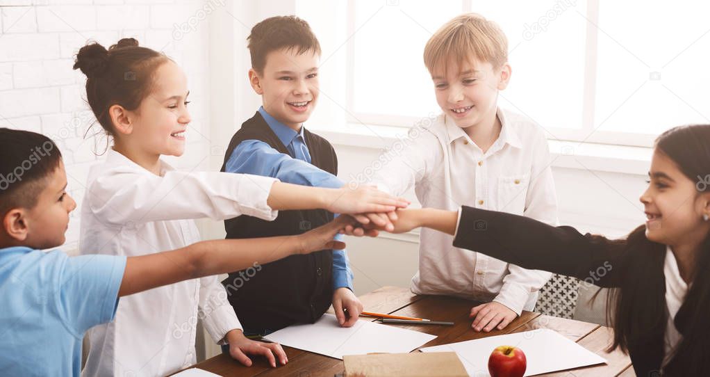 School children putting their hands together indoors