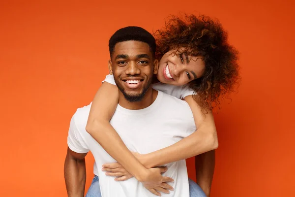 Söta par i kärlek omfamna på orange bakgrund — Stockfoto