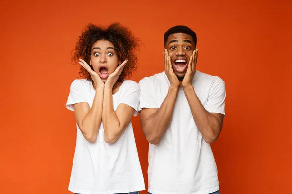 Chockad känslomässiga afro-amerikanska paret på orange bakgrund — Stockfoto