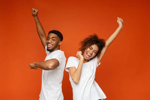 Emotional black man and woman dancing on orange — Stock Photo, Image