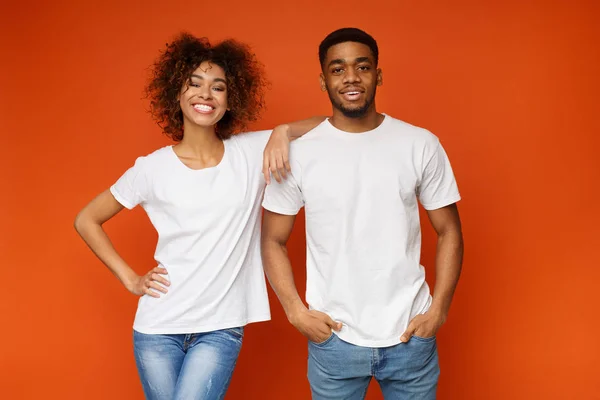 Vrolijke zwarte jongen en meisje die zich voordeed op oranje studio achtergrond — Stockfoto