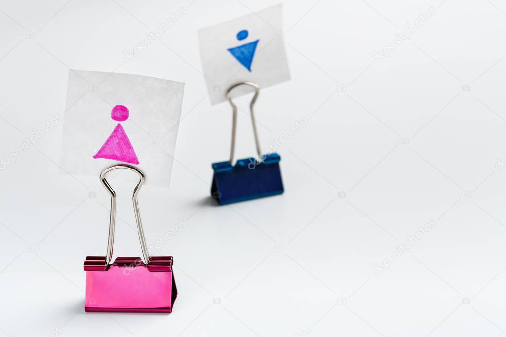 Female figure on pink binder clip leading male
