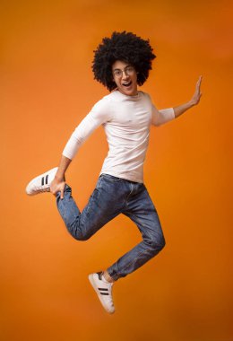 Turuncu studio arka plan üzerinde atlama mutlu zenci