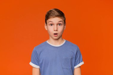 Portrait of stunned boy on orange studio background clipart