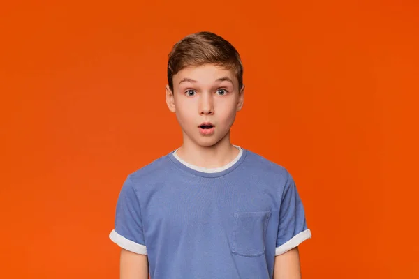 Portret van verbijsterd jongen op oranje studio achtergrond — Stockfoto