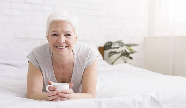 在床上享受热咖啡的高级妇女 — 图库照片