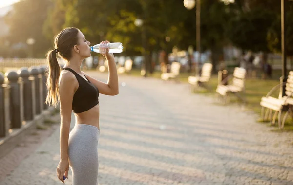 Deportiva haciendo descanso en correr, beber agua en muelle — Foto de Stock