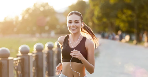 Vrolijke vrouw met hoofdtelefoon uitgevoerd in park — Stockfoto