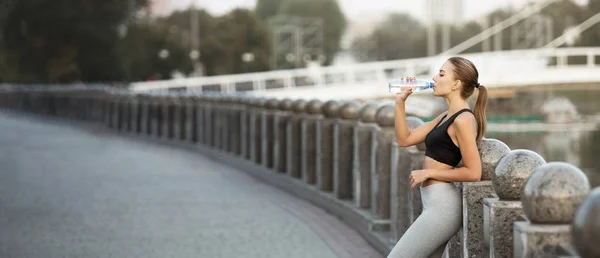 Deportiva milenaria bebiendo agua después de correr la práctica en el puente — Foto de Stock
