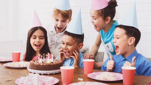Дитяча вечірка на день народження. Хлопчик вибухає свічки на торт — стокове фото