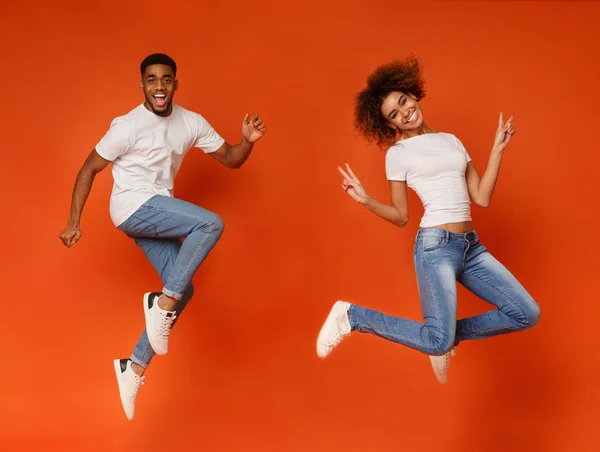 Cheerful african-american guy and girl running in air — Stock Photo, Image