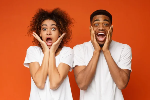 Verbaasd zwarte man en vrouw openen van mond en wangen aan te raken — Stockfoto