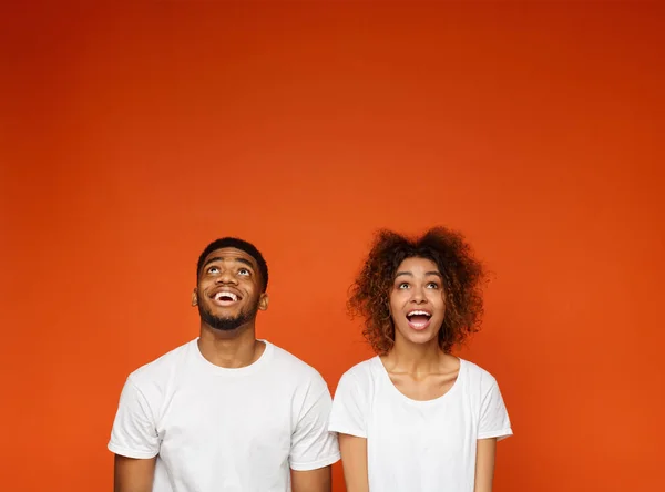 Homem e mulher afro-americanos entusiasmados olhando para cima — Fotografia de Stock