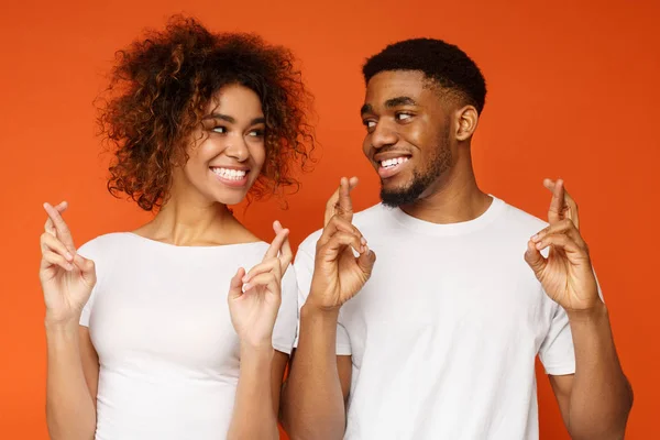 Lindo hombre negro y mujer con los dedos cruzados pidiendo deseo — Foto de Stock