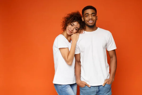 Härlig afro-amerikanska par kramas på orange bakgrund — Stockfoto