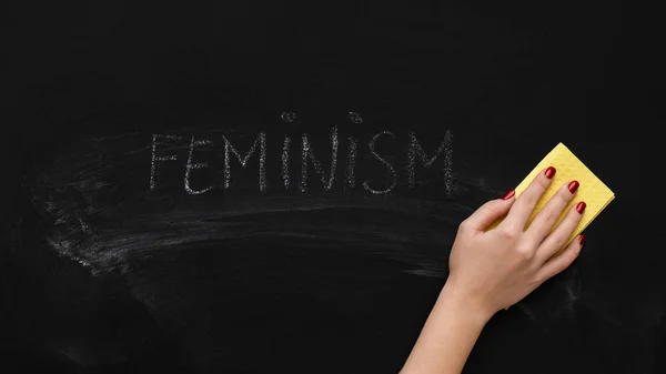 Woman cleaning word FEMINISM on chalkboard, panorama — Stock Photo, Image