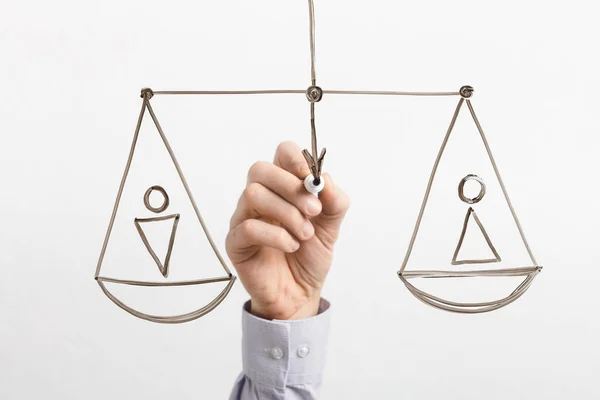 Man drawing equal scales with male and female figures on glassboard — Stock Photo, Image