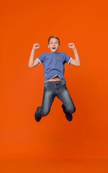 Выразительный взволнованный мальчик наслаждается успехом прыгая в воздух — стоковое фото