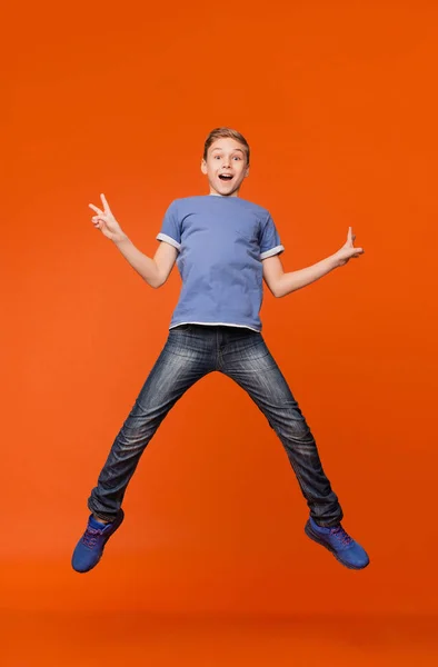 Fröhlicher Junge springt in die Luft und demonstriert V-Zeichen — Stockfoto