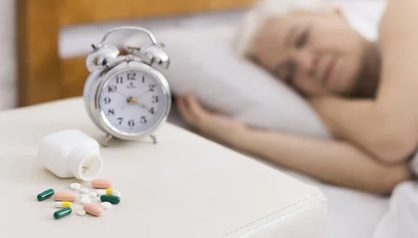 Senior mulher dormindo na cama com a ajuda de pílulas — Fotografia de Stock