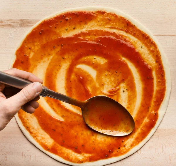 Chef adding sauce, spreading tomato paste on pizza base — Stock Photo, Image