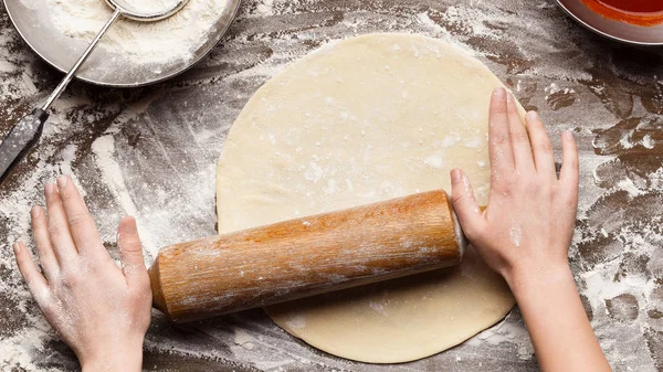 Жінка готує тісто для піци на столі, вид зверху — стокове фото