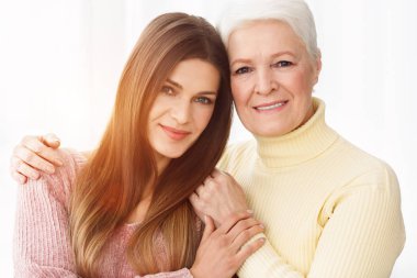 Sevgi dolu bir anne ve kızı sarılma ve kameraya bakıyor