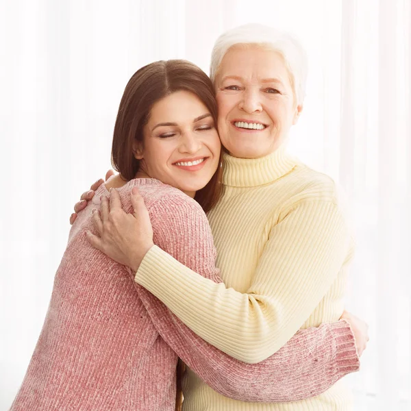 Süße kleine Tochter umarmt ihre Mutter mit Liebe — Stockfoto