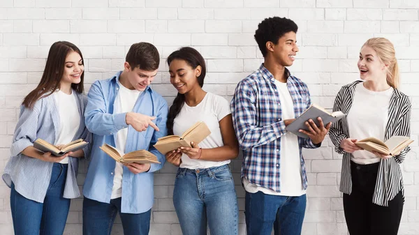 Concepto de aprendizaje. Adolescentes con libros de pie cerca de la pared de luz —  Fotos de Stock