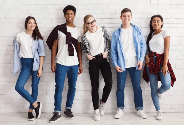 Amigos con estilo. Grupo de estudiantes posando sobre pared blanca —  Fotos de Stock