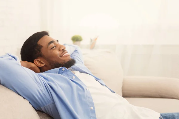 Handsome african-ameriacn man relaxing on sofa at home — Stock Photo, Image