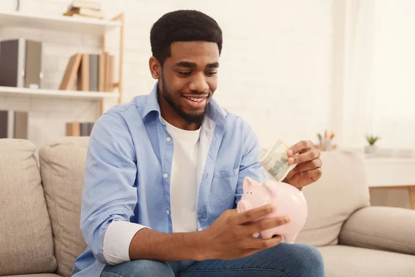 Hombre poniendo billete de dólar en alcancía — Foto de Stock