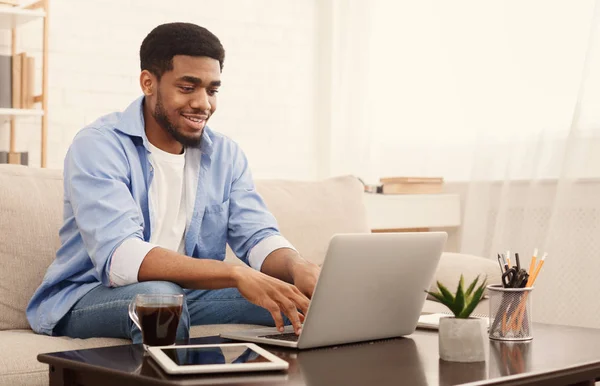 Χιλιετή μαύρο άνθρωπος που εργάζονται στο lap-top στο γραφείο στο σπίτι — Φωτογραφία Αρχείου