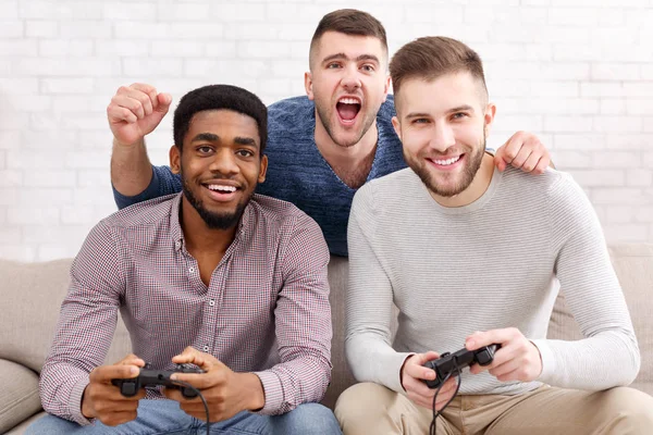 Геймеры. Возбужденные мужчины играют в видеоигры дома — стоковое фото