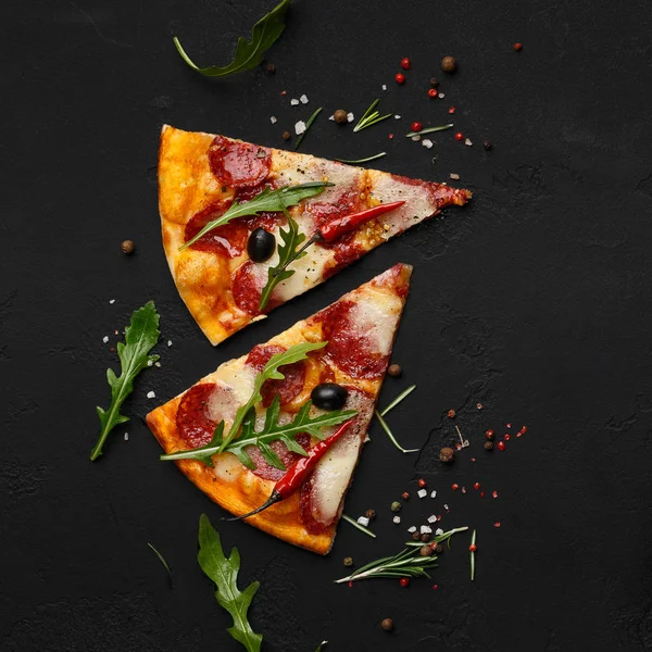 Rebanadas de pizza con ensalada de rúcula sobre fondo negro — Foto de Stock