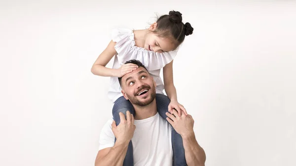 Menina bonito sentado em seus ombros pai e sorrindo para ele — Fotografia de Stock