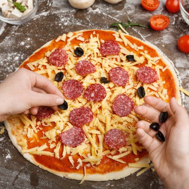 Aşçı pizzaya siyah zeytin ekleyerek, dekorasyon