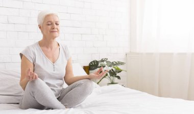Genç kadın lotus pozisyonu yatakta oturup meditasyon