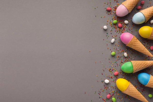 Huevos coloridos de Pascua en conos de gofre sobre fondo gris —  Fotos de Stock